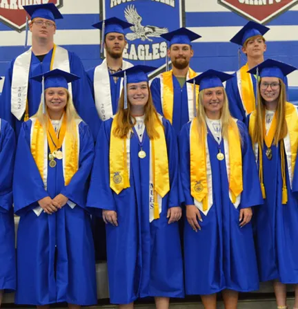 A group of graduates in blue and gold graduation gowns, celebrating their academic achievement.